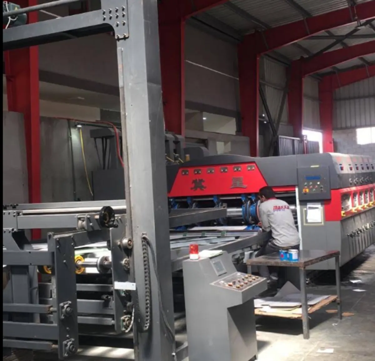 Multi-unit flexo printer-slotter running board, operator at the feed station.